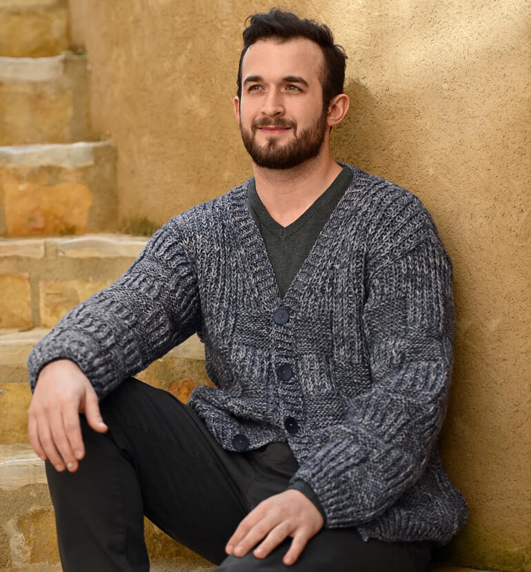 Mann trägt einen grauen Herrencardigan aus Linie 517 Talon und sitzt entspannt.