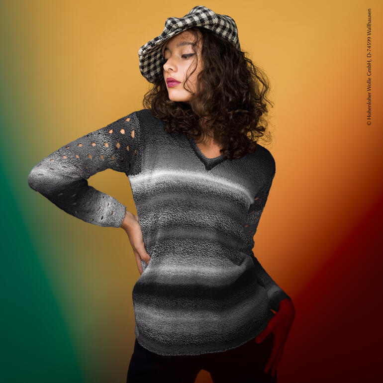 Frau trägt einen gestreiften Pullover aus Edition 6 von Schoppel Wolle in einem stilvollen Raum.