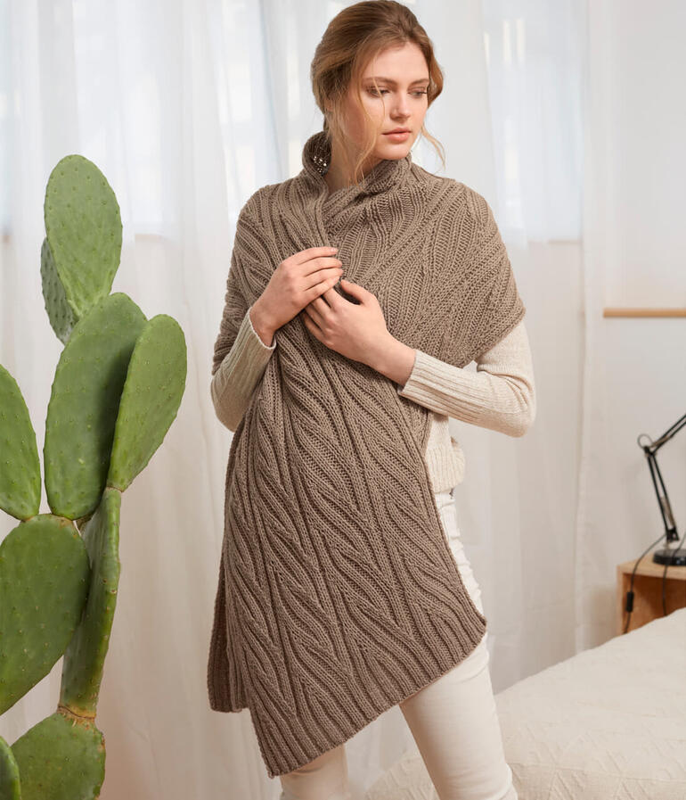 Frau zeigt eine Stola mit Zopfmuster in einer hellen Umgebung