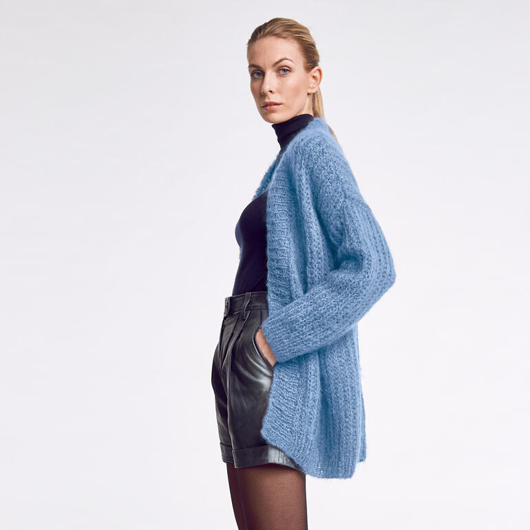 Frau in einer blauen, lockeren Jacke mit langen Ärmeln