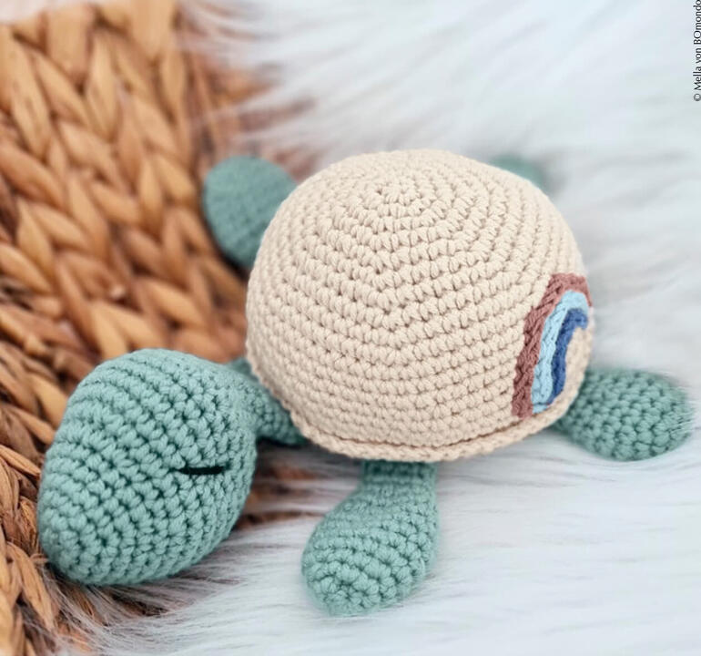 Gehäkeltes Kuschltier Schildkröte in sanften Farben auf einem Geflecht