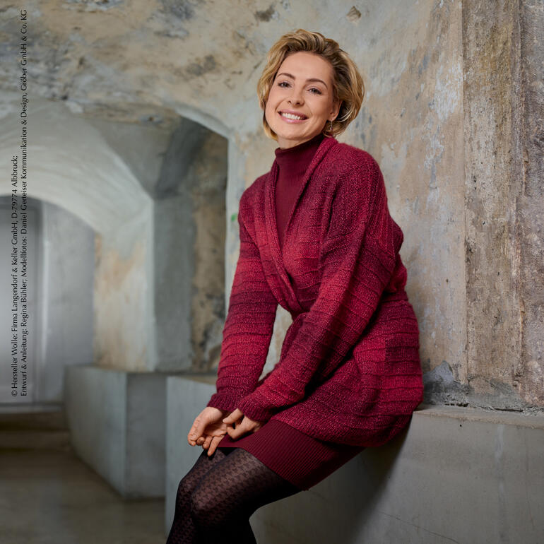 Lächelnde Frau in roter Jacke mit Gürtel sitzt auf dem Sofa.