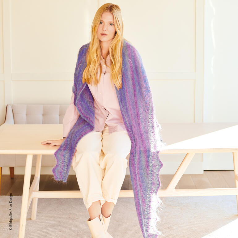 Buntes Dreiecktuch aus Mohair auf einer Frau, die an einem Tisch sitzt.