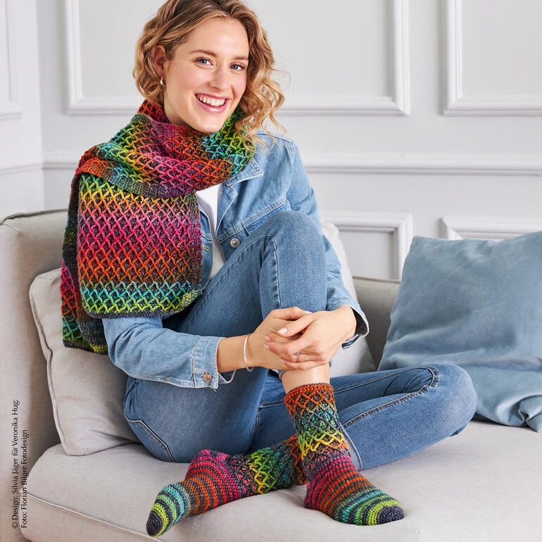 Bunt gehäkelter Schal und Socken auf einer Frau, die lächelt.