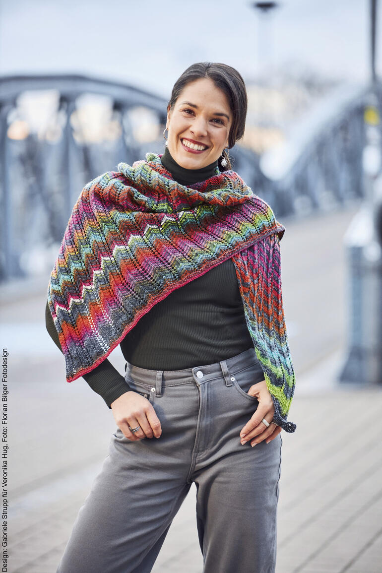 Buntes Tuch aus Mohair, getragen von einer lächelnden Frau am Hafen.