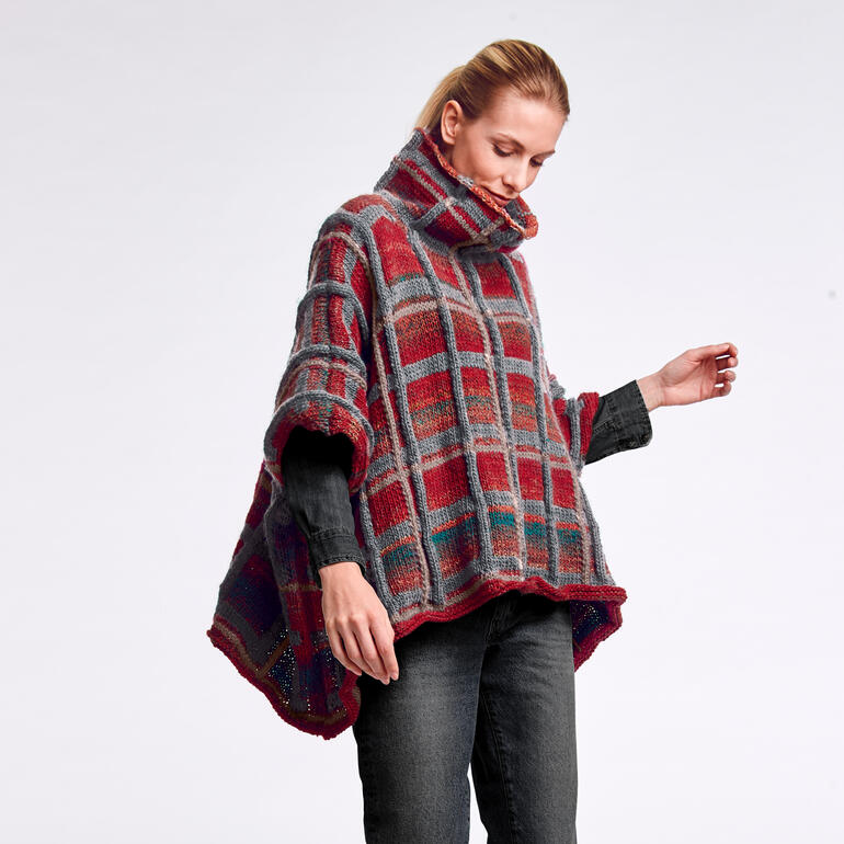 Rotes und graues Poncho-Cape mit Karomuster, getragen von einer Frau.