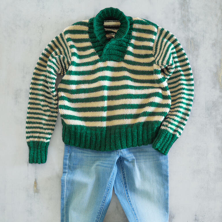 Gestreifter Pullover aus Enny, flach auf einem Tisch liegend mit einer Hose.