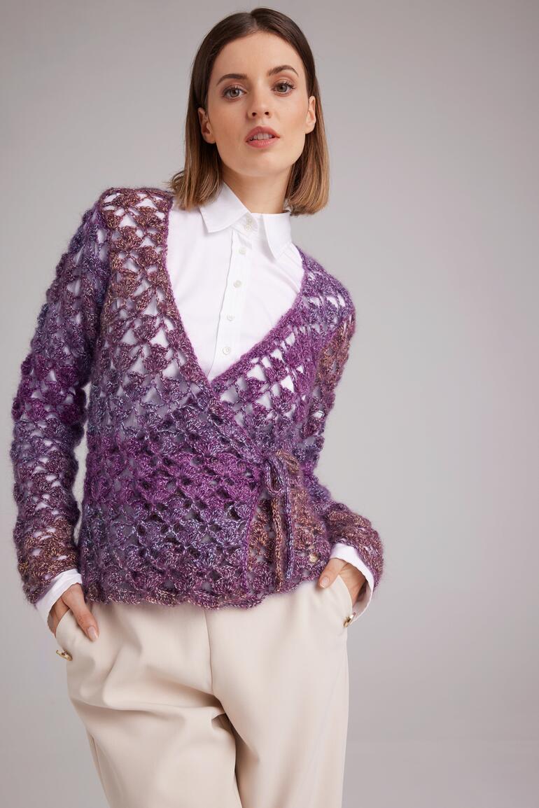 Frau trägt eine gehäkelte Wickeljacke aus Aparta-Print in eleganter Pose.