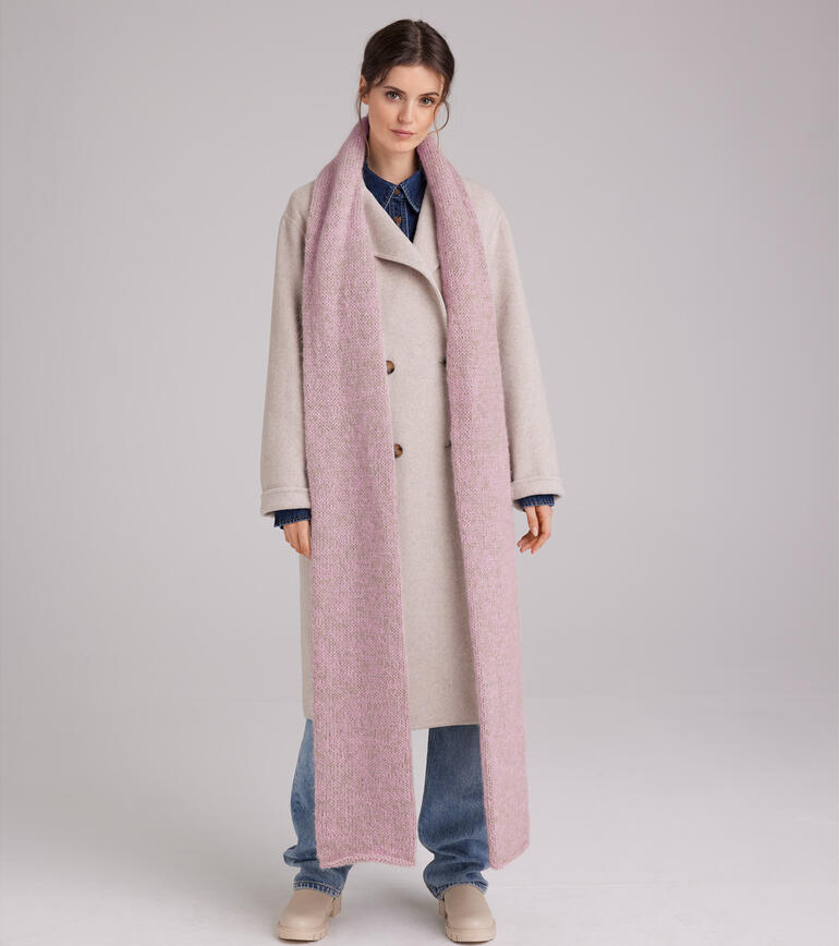 Frau in beiger Jacke trägt einen rosa Schal und lächelt in die Kamera.