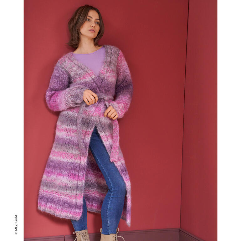 Frau trägt einen langen, gemusterten Mantel in lila Tönen und sieht selbstbewusst aus.