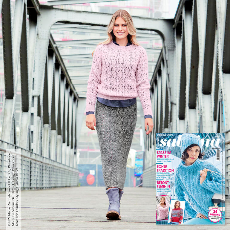 Model trägt einen strickten Pullover und einen langen Rock, geht auf einer Brücke.