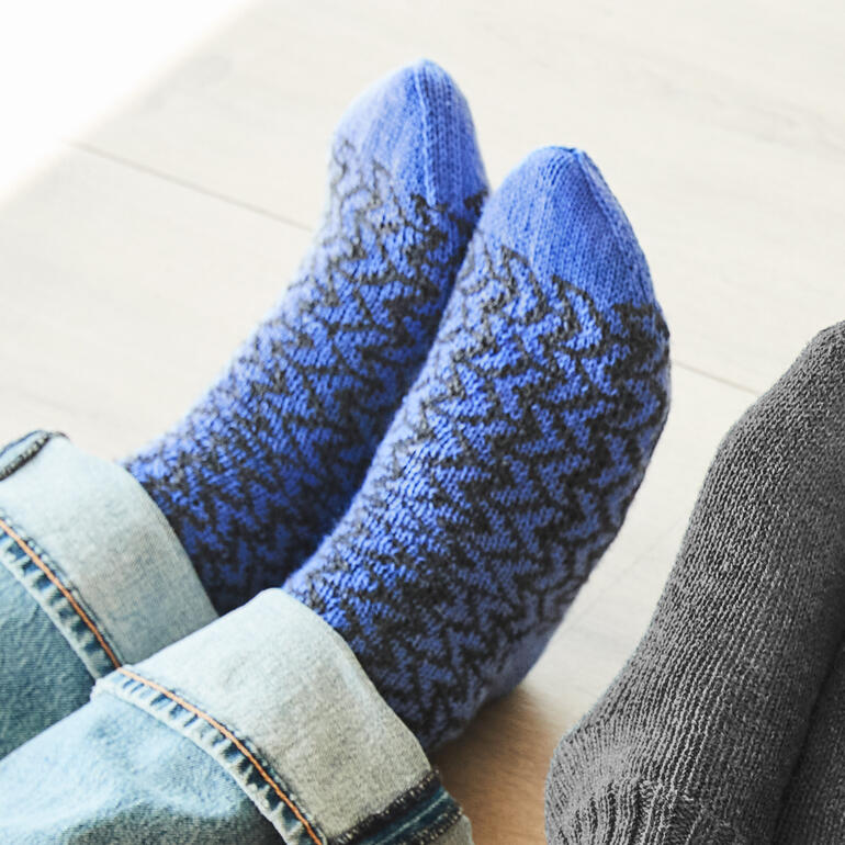 Blaue Socken mit Zickzack-Muster aus Merino-Freizeit Wolle, auf einem hellen Boden