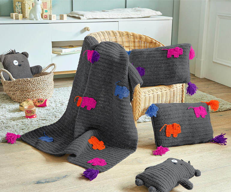 Bunte Decke und zwei Kissen aus Poco, dekoriert mit tierischen Motiven.