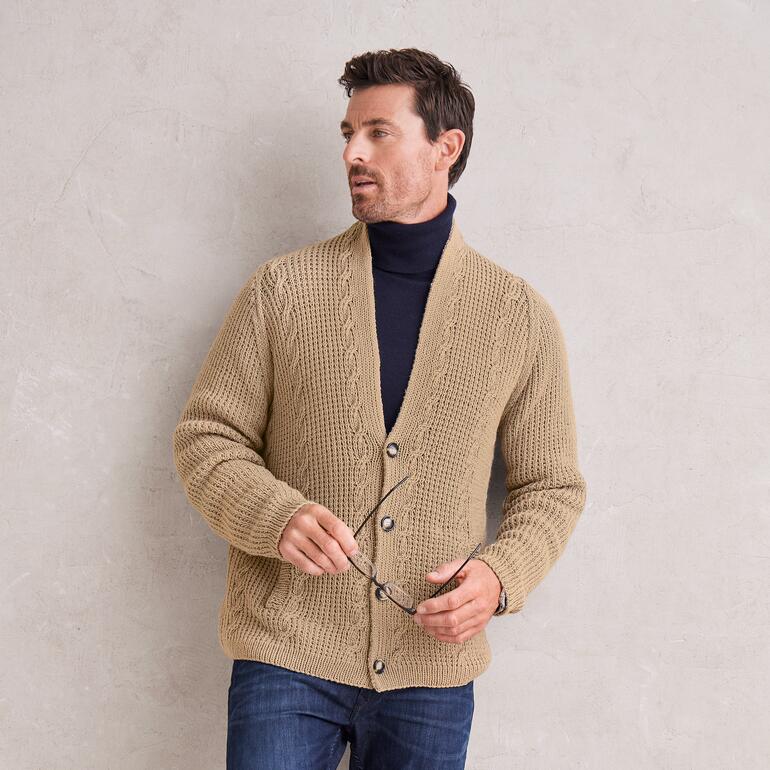 Mann in beiger Raglan-Herrenjacke aus Merino-Cotton posiert an einer Wand.