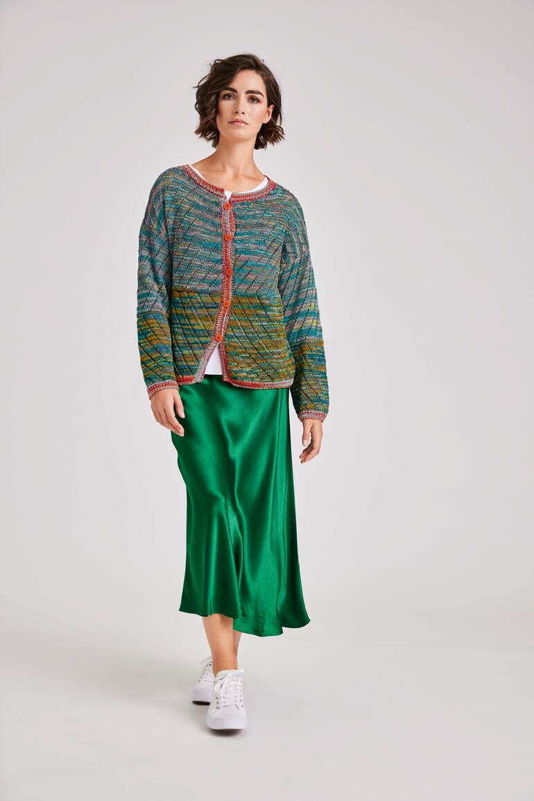 Frau in farbenfroher Jacke mit roten Akzenten, geht auf einem hellen Hintergrund.