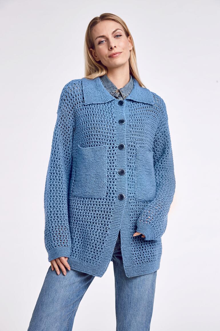 Frau in blauer Overjacket mit großen Taschen, steht lässig zur Kamera.