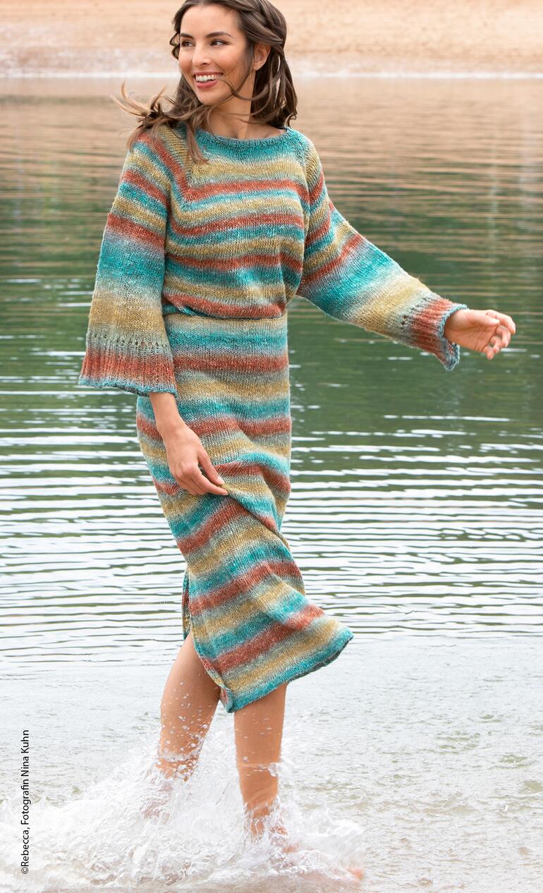 Frau in gestreiftem Pullover und Rock am Wasser läuft und sieht natürlich aus.