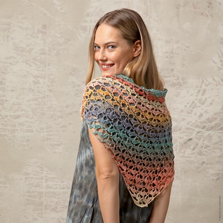 Frau trägt drapiertes, farbenfrohes Dreiecktuch und schaut über die Schulter.