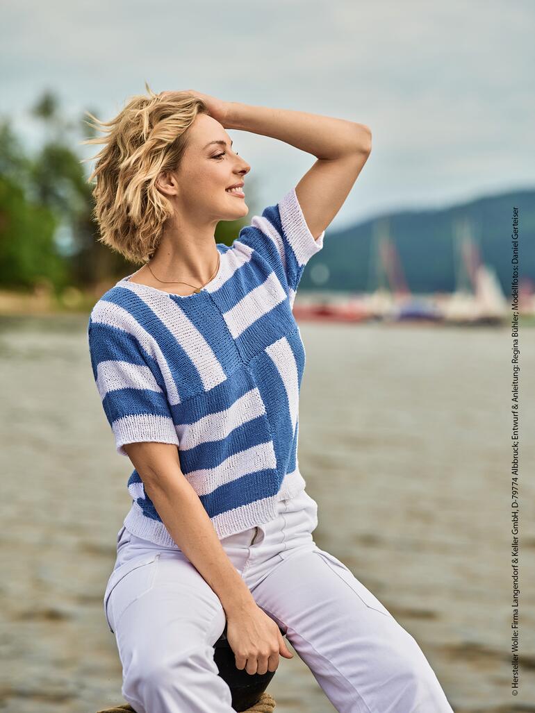 Damen-Pulli aus Natural Logic, blau gestreift und lässig am Wasser sitzend.