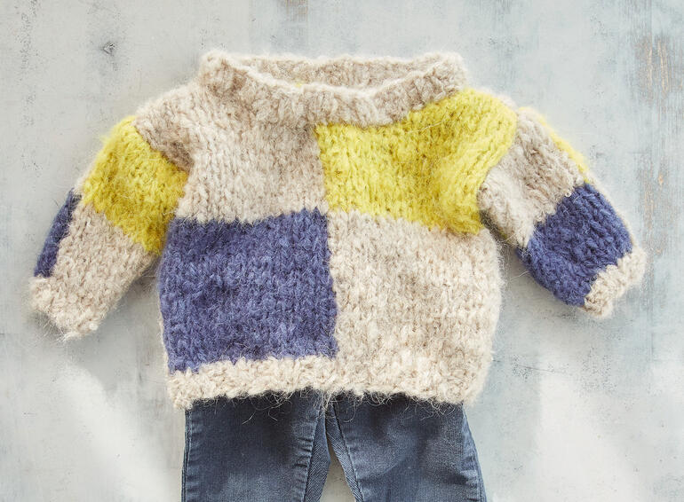Bunter Babypullover aus Nappy mit verschiedenen Farbfeldern.