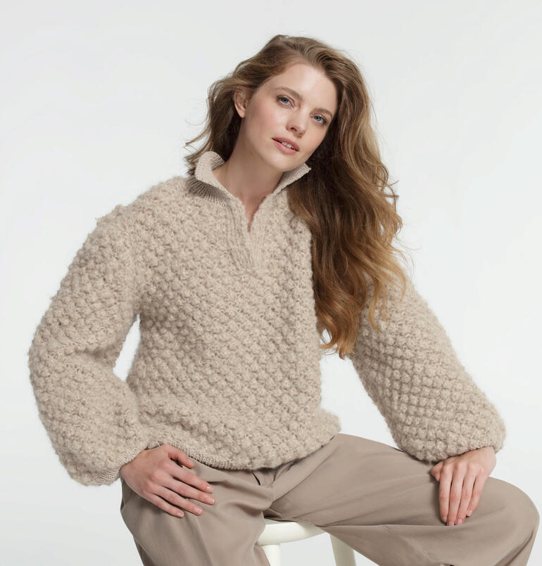 Polo-Pullover aus Nappy und Merino in beige, getragen von einer Frau mit langen Haaren.