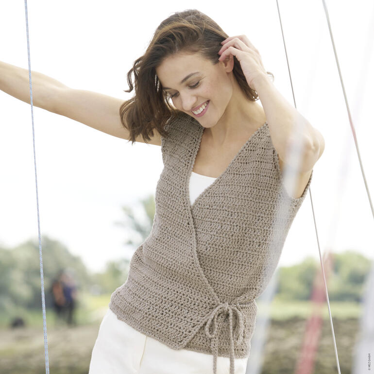 Gehäkelte Wickelweste in braun, getragen von einer Frau auf einem Segelboot.