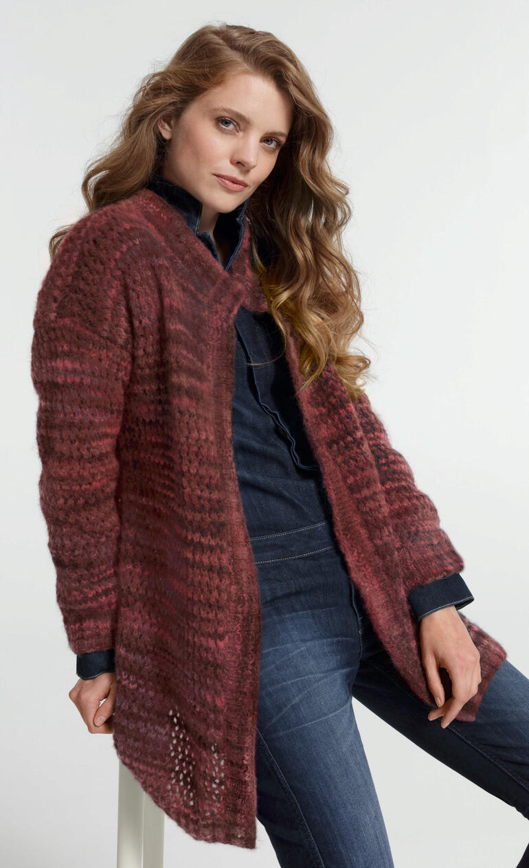 Frau in braunem Mantel, sitzt in einer lässigen Pose.