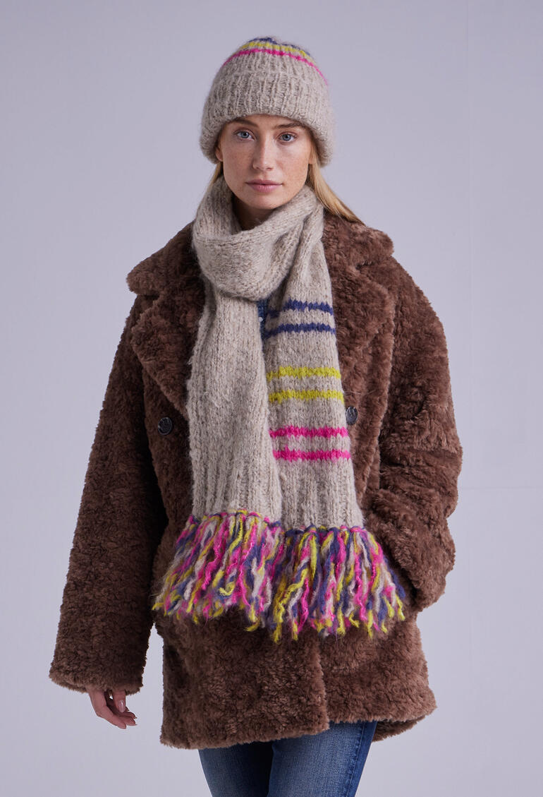 Frau trägt Mütze und Schal aus Nappy mit bunten Fransen.