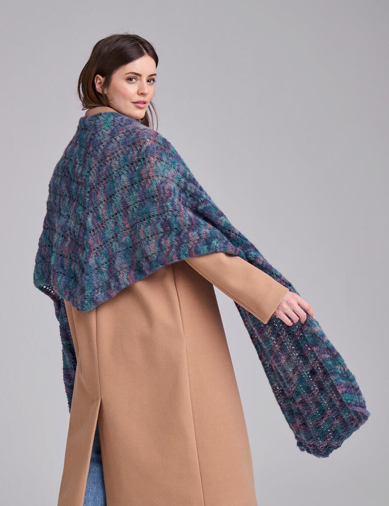 Schultertuch aus Flou in Türkis mit lila, getragen von einer Frau in beigem Mantel.