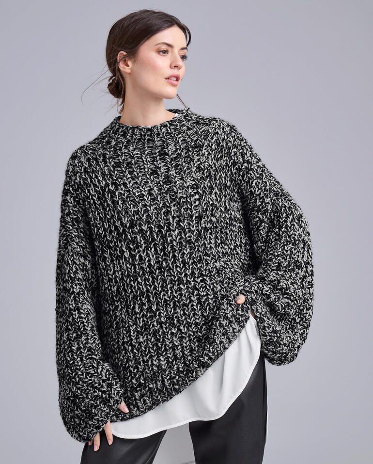 Dunkelgrauer Pullover mit weiten Ärmeln gegen hellen Hintergrund.