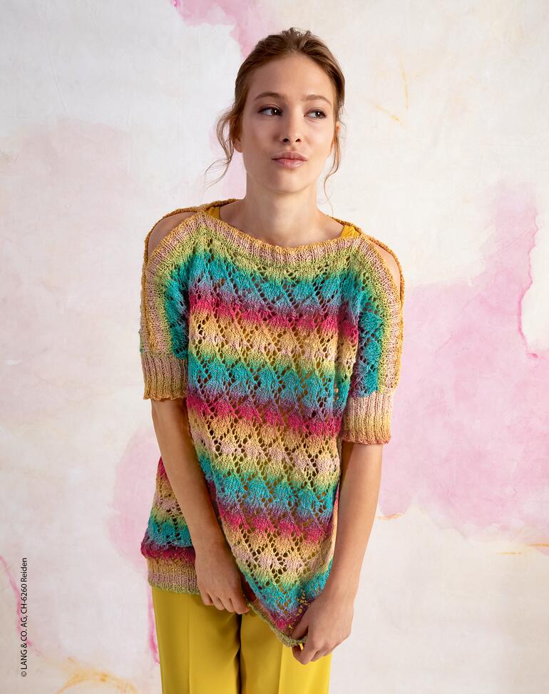 Frau in buntem Pullover aus Linello vor pastellfarbenem Hintergrund.