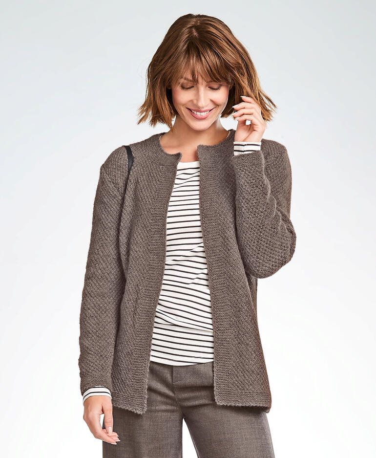 Frau in kastanienbrauner Jacke aus Kaschmir lächelt vor neutralem Hintergrund.