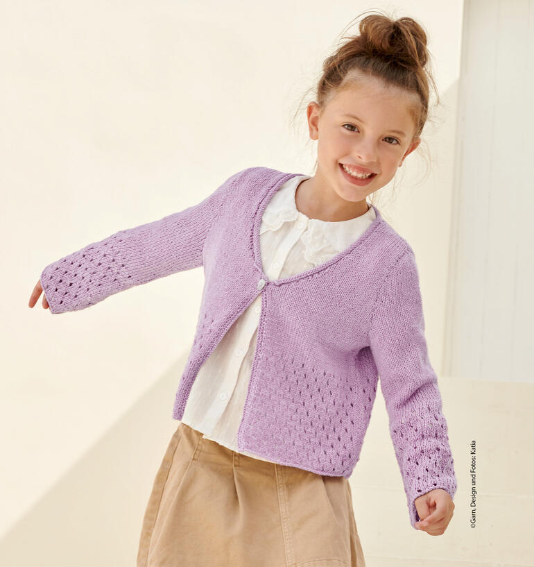 Lächelndes Mädchen in lila Kinderjacke aus Eunoia, die spielerisch die Arme ausbreitet.