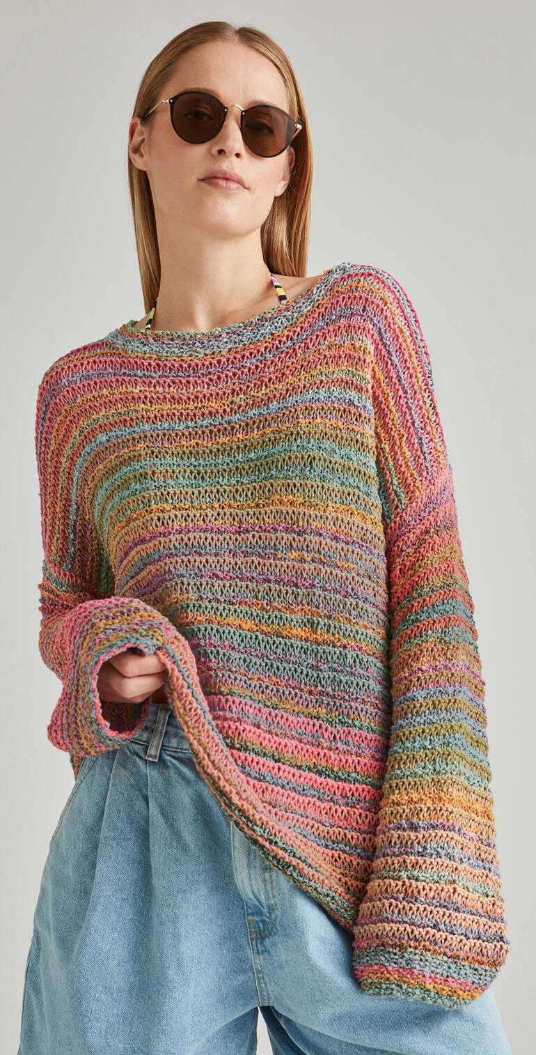 Frau trägt einen bunten, lässigen Pullover in sanften Farben.