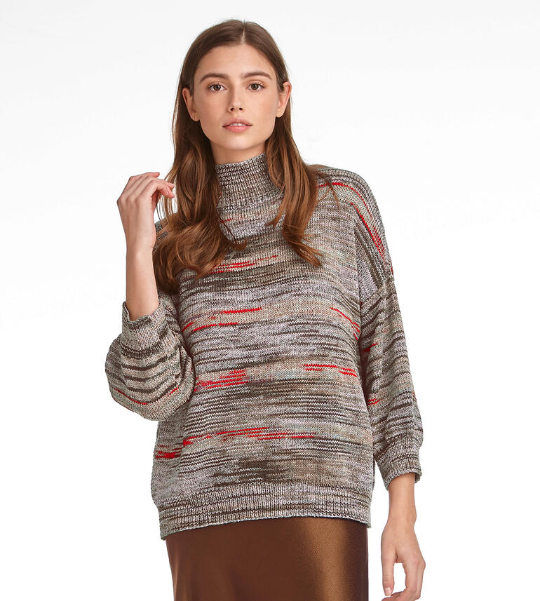 Frau in grauem Pullover mit bunten Akzenten, posiert für die Kamera.