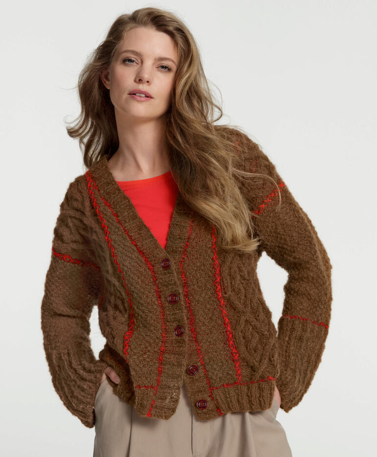 Frau in brauner Aerea Jacke mit rotem Oberteil