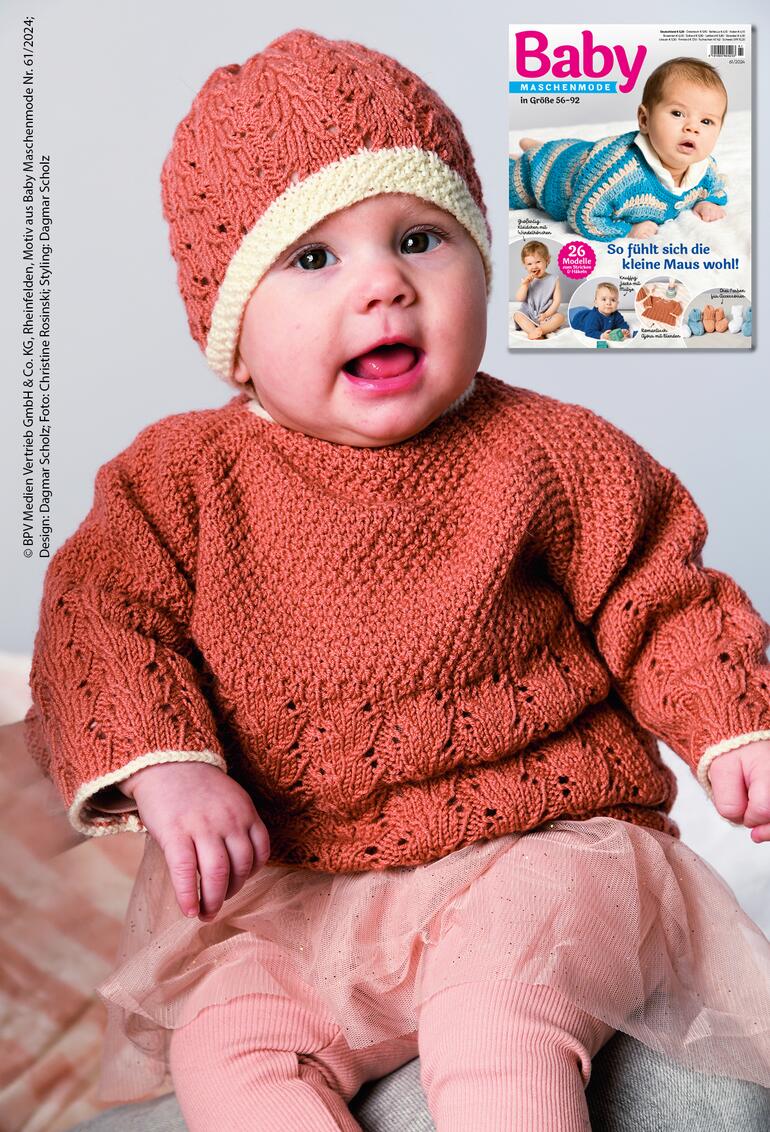 Babypulli mit Mütze in rot aus Nuovo Merino 180, getragen von einem lächelnden Baby.