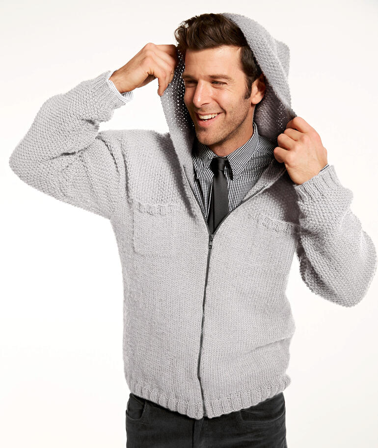 Hellgraue Herrenjacke mit Kapuze aus Merino-Classic, ein Mann zieht die Kapuze an.