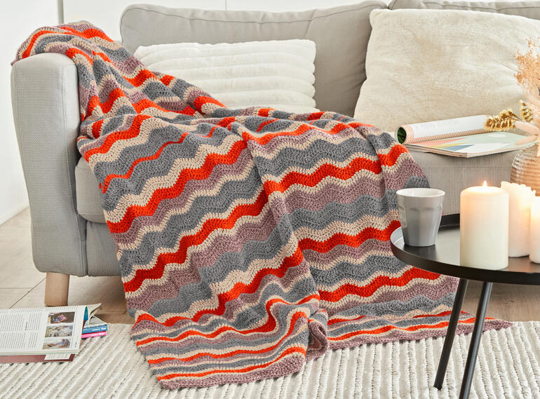 Bunte Decke aus Monello-175 Uni, über einem grauen Sofa drapiert, mit Kerzen und Zeitschriften.