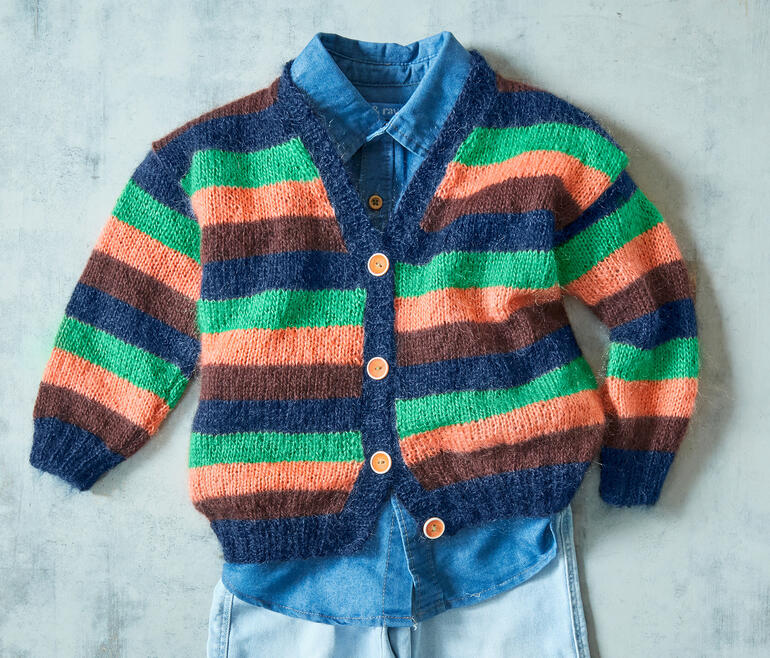 Bunte Kinderjacke aus Aparta von Junghans-Wolle neben einem blauen Hemd.