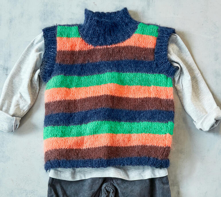 Gestreifter Kinderpullunder aus Aparta von Junghans-Wolle neben einem grauen Shirt.