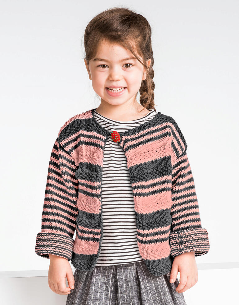 Lächelndes Mädchen trägt eine gestreifte Kinderjacke aus Cotonara von Junghans-Wolle.