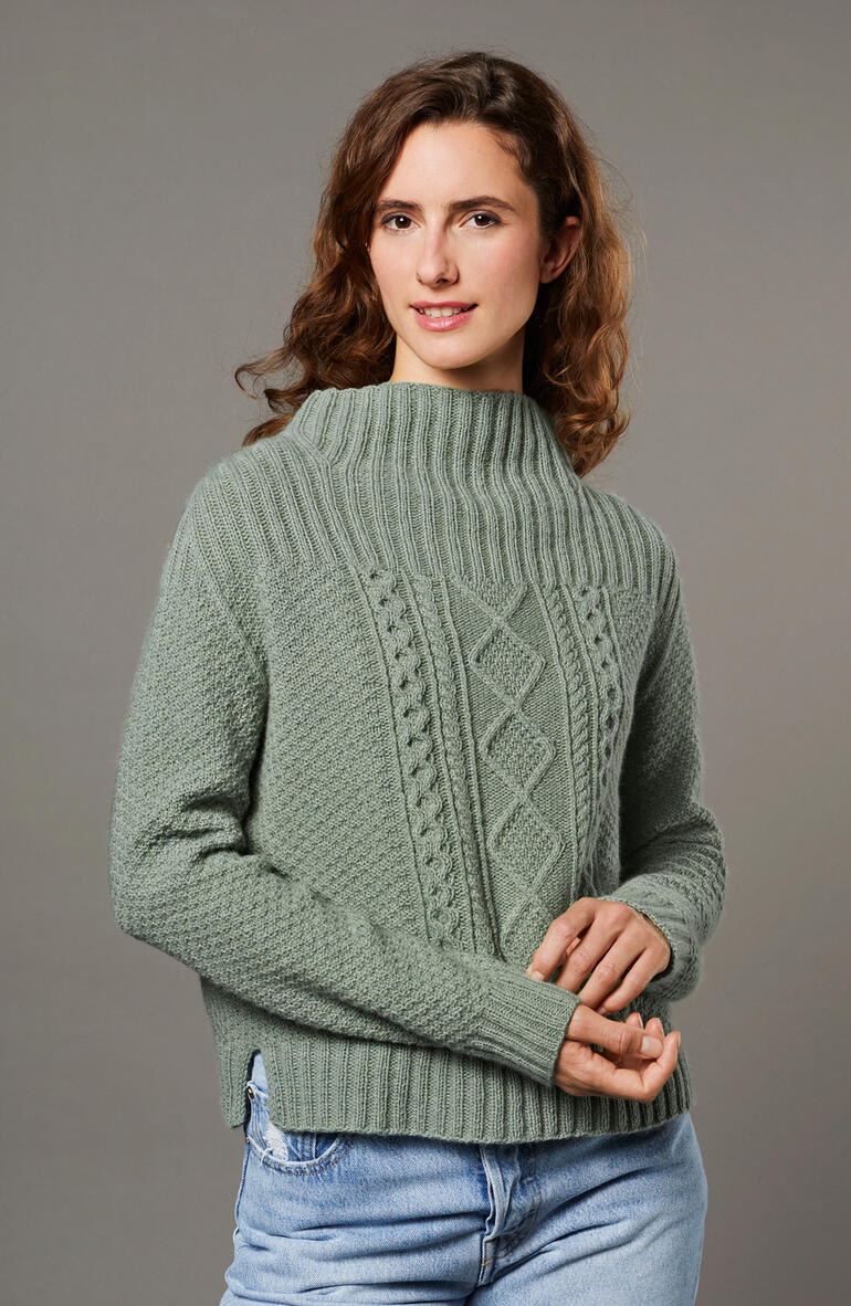 Frau trägt einen eleganten Pullover aus Como von Lamanaund in einem sanften Grünton.