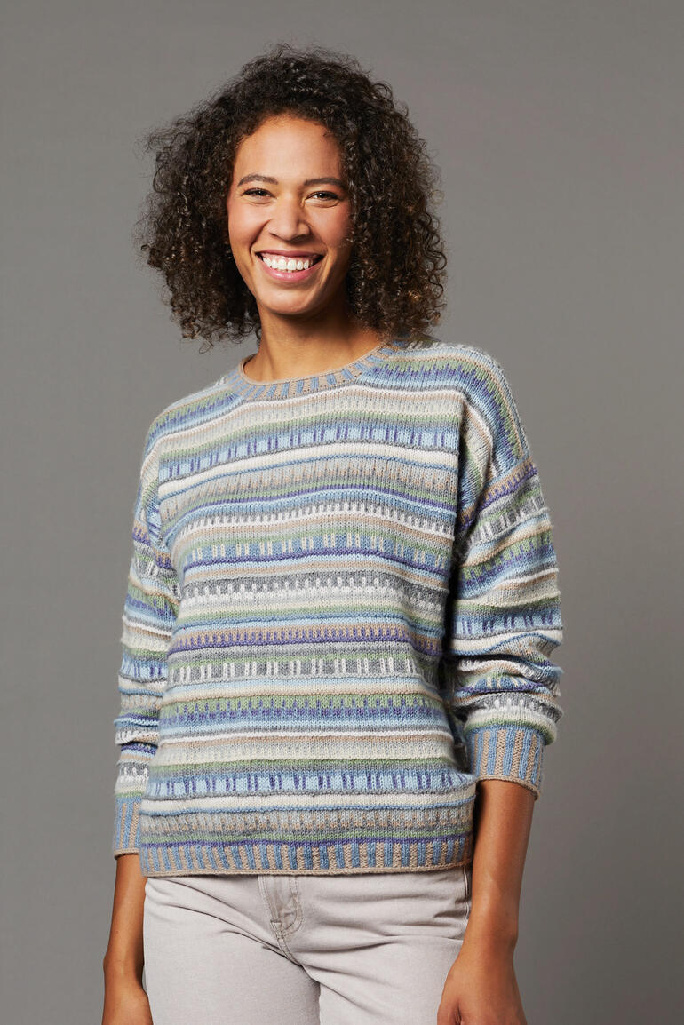 Frau lächelt in einem bunten Pullover aus Como von Lamanaund mit Streifen.