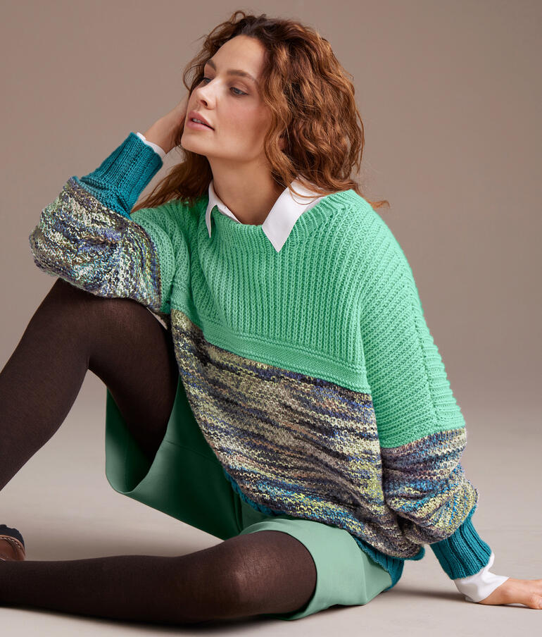 Bunter Pullover aus Merino-Print und Nuovo Merino 120, lässig über einer hellen Hose getragen.