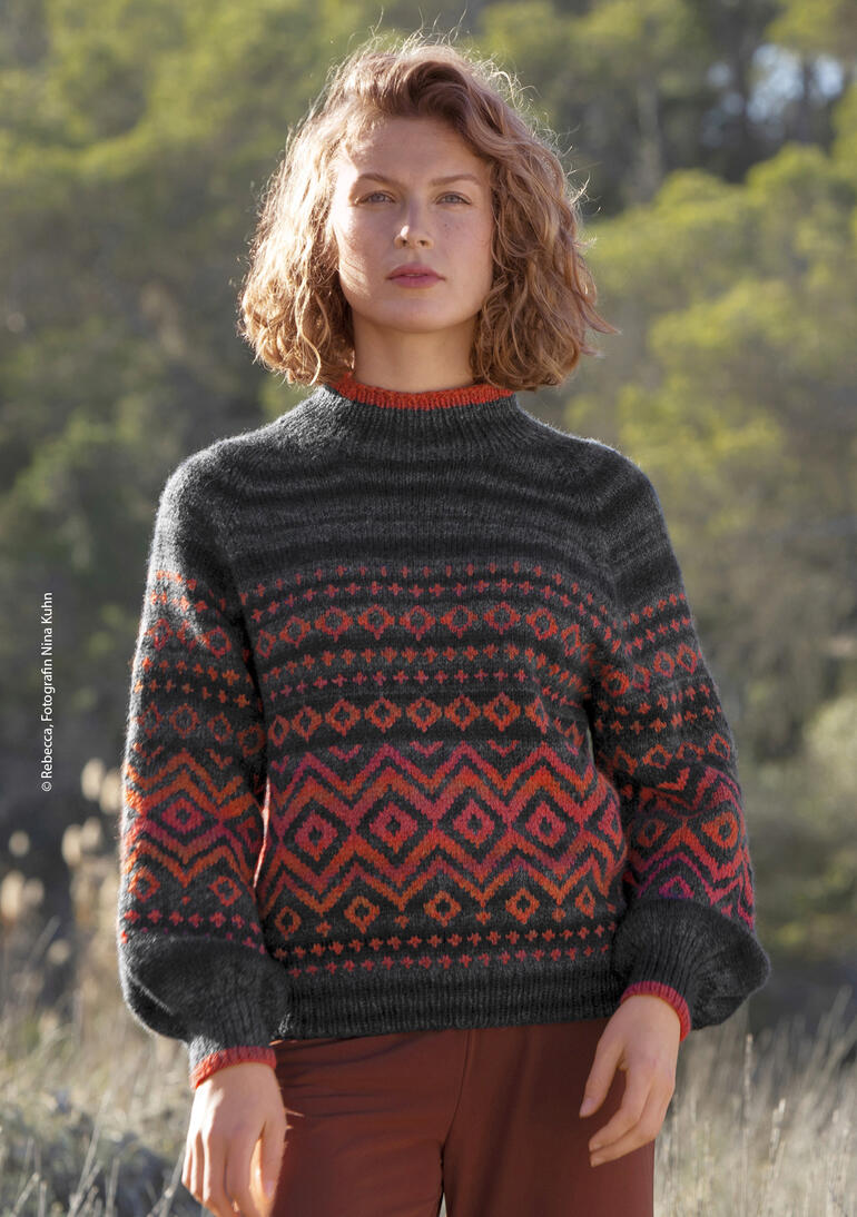 Gemusterter Pullover aus Akina, in gedeckten Farben und elegant im Freien getragen.