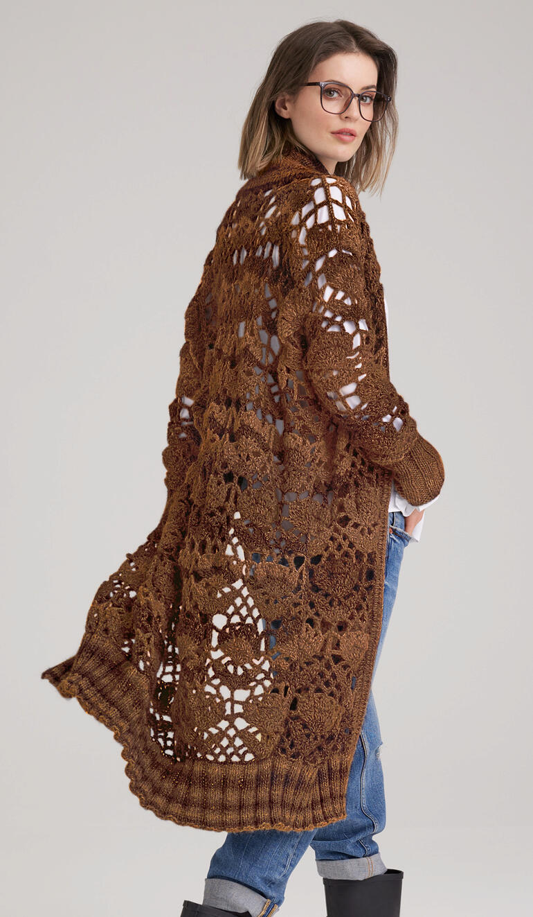 Lange Jacke aus Scala mit offenen Maschen, lässig über einer Jeans getragen.