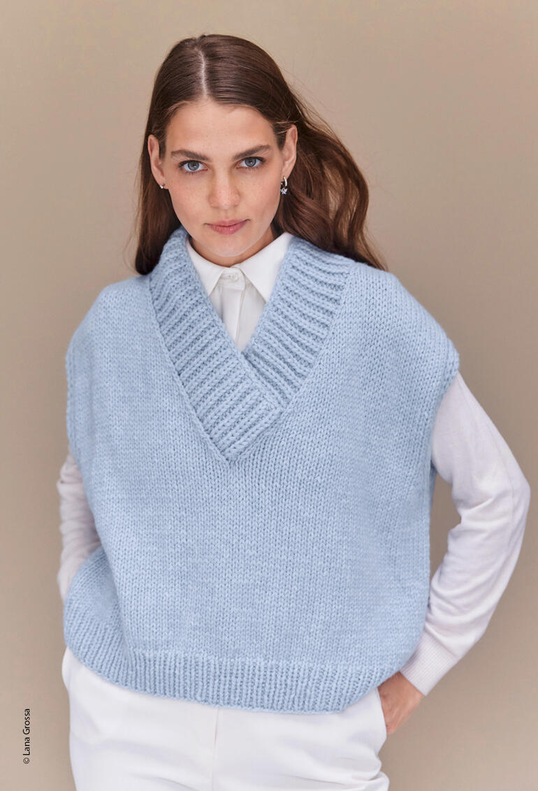 Frau in hellem Pullunder aus Cool Merino Big, schaut direkt zur Kamera.