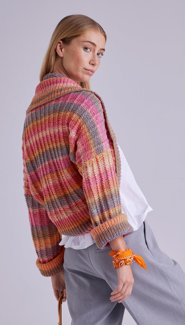 Frau in buntem Bolero drapiert, mit Blick über die Schulter.