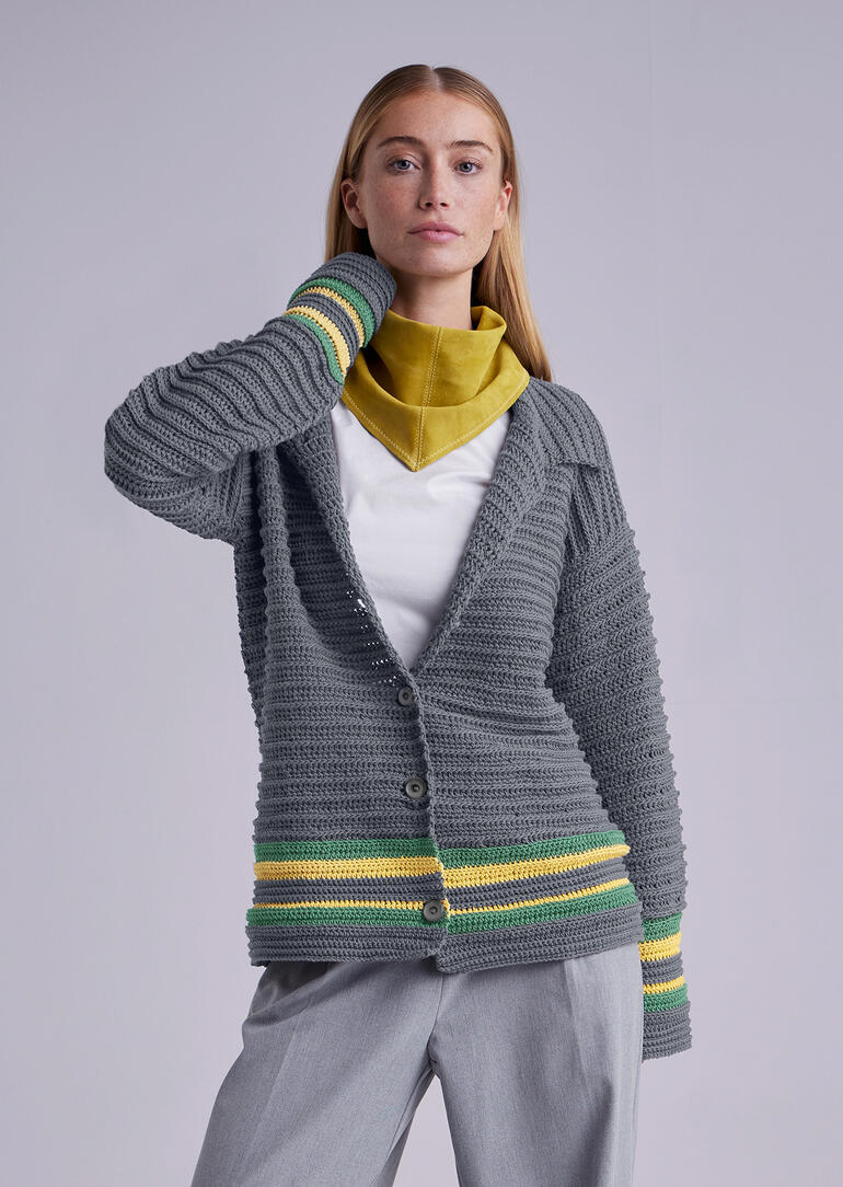 Frau in grauer Jacke, die an den Ärmeln gestreift ist und die Schultern freilässt.